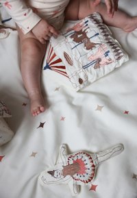 Biała bawełniana narzuta z różowym i brązowym haftem, przedstawiająca wzory zwierząt i kolorowe gwiazdki. Pluszowa zabawka przypomina tancerkę, z detalicznym przeszyciem.