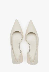 Špičaté lodičky v jemně béžové kůži s výřezem na bocích a hladkým povrchem. Vnitřek má jemně vzorovanou podšívku.