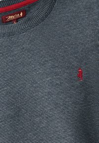 Suéter de punto azul oscuro con un patrón texturizado, presenta un cuello redondo y un pequeño logotipo rojo bordado en el pecho.