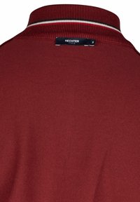 Bordová polo košile s texturovanou tkaninou, žebrovaným límcem s červenými a bílými pruhy a černou nášivkou s nápisem "HECHTER PARIS."