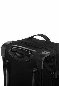 Valigia nera in tessuto con maniglia superiore, chiusura con zipper e dettagli in plastica. Presenta ruote resistenti per la mobilità e un design compatto.