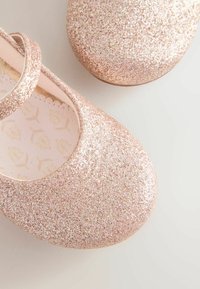 Rózsaszín csillogó balettcipők lekerekített orral és állítható pánttal. Textúrált felsőrész, puha bélés levélmintával és lapos talppal.