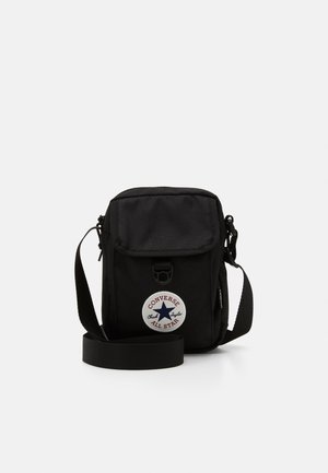 Borsa a spalla nera in tela con chiusura a pattina, tracolla regolabile e un grande patch circolare con il logo Converse.
