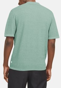 Lühikeste varrukatega polo särk heleses rohelises, tekstuurse kootud kangaga, klassikalise krae ja peene logodetailiga allääres.