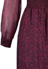 Robe bordeaux à manches longues avec tissu transparent aux manches et imprimé floral sur le corsage et la jupe.