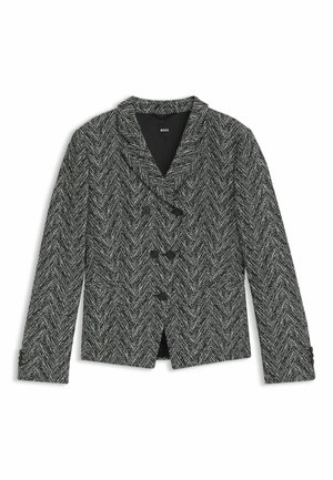Sorte og hvide hælrette mønstrede blazer med store udskæringer, dobbeltradede knapper og sidelommer. Tekstureret stoffinish.