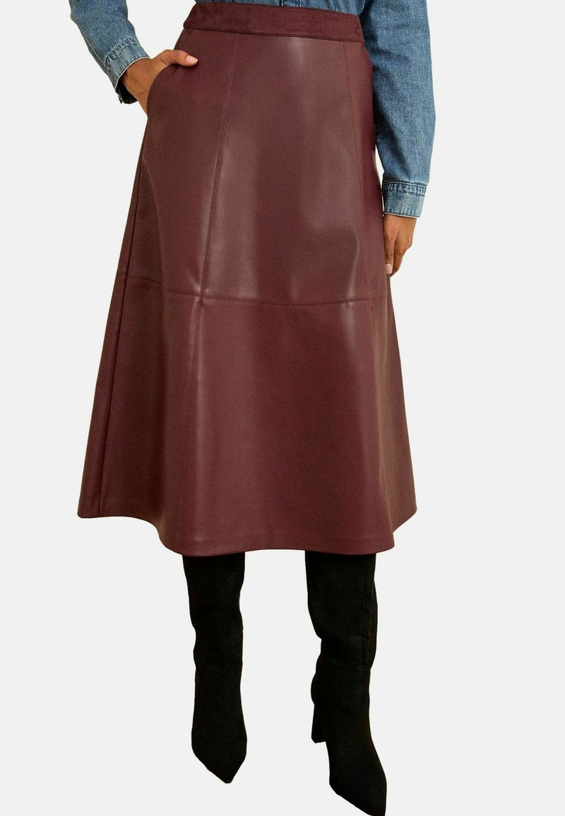 Bordeauxfarbene Leder-Midikleider mit schwingendem Schnitt, glatter Textur und Nahtdetails, kombiniert mit schwarzen kniehohen Stiefeln.