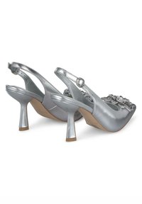 Tacchi slingback argento con tacco stiletto basso, caratterizzati da un accento floreale decorativo sulla punta e una texture lucida e liscia.