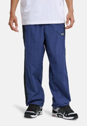 Niebieskie, lekkie nylonowe spodnie cargo z czarnymi akcentami po bokach, dwoma przednimi kieszeniami oraz okrągłym logo po lewej stronie.