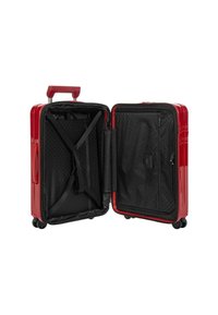 Valigia rigida rossa con finitura lucida, rivestimento interno nero, cinghie incrociate, tasca con zip e quattro ruote per una facile mobilità.