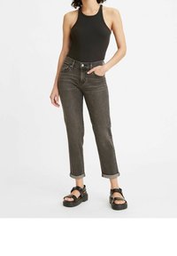 Top de tirantes negro con textura acanalada y cuello alto, combinado con jeans rectos gris oscuro con dobladillos vuelta y sandalias de plataforma negras.