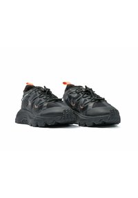 Zapatillas deportivas negras con material superior texturizado, suela de goma gruesa y acentos en naranja. Diseñadas para ofrecer tracción con un diseño robusto.