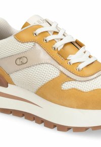 Baskets avec une tige en mesh et en suède blanc et jaune, dotées d'un panneau beige brillant, de lacets blancs et d'une semelle intermédiaire blanche épaisse avec des accents marron.