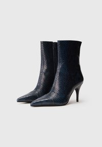 Botines de punta afilada en faux serpiente azul oscuro con una silueta elegante, cierre de cremallera en la parte posterior y un tacón delgado y alto.