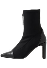 Bottines noires avec une tige en textile lisse, bout pointu et talon aiguille. Dotées d'une fermeture éclair sur le côté. Design épuré et minimaliste.