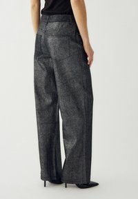 Sive široke hlače s teksturiranim završetkom, s pojasom srednje visine i dva stražnja džepa. Nosive s crnim petama.