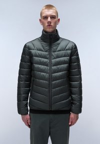 Vadderad jacka i mörkgrått, med hög krage, vertikal quilt-design, hel dragkedja fram och elastiska ärmmuddar.