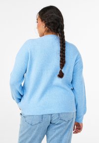 Svetlo moder rebrast pulover z udobnim splošnim krojem in dolgimi rokavi, izdelan iz mehke tkanine. Podrobni šivi ob šivih.