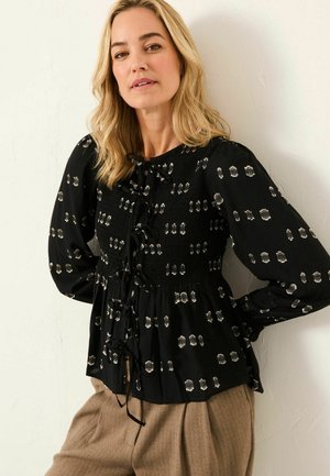 Schwarze Bluse mit metallischen Akzenten, gerafftem Oberteil und Bandbindern. Lange Ärmel mit gerafften Manschetten und einer lockeren, fließenden Passform.