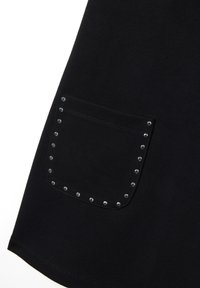 Vêtement noir avec une poche à rabat ornée de clous argentés sur le bord, fabriqué dans un tissu lisse avec un léger éclat.