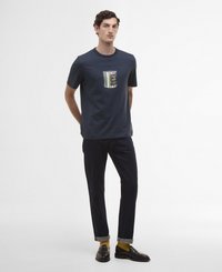 T-shirt de algodão azul-marinho com um design de bolso riscado, combinada com jeans escuros e sapatos pretos, apresentando punhos enrolados e meias amarelas.