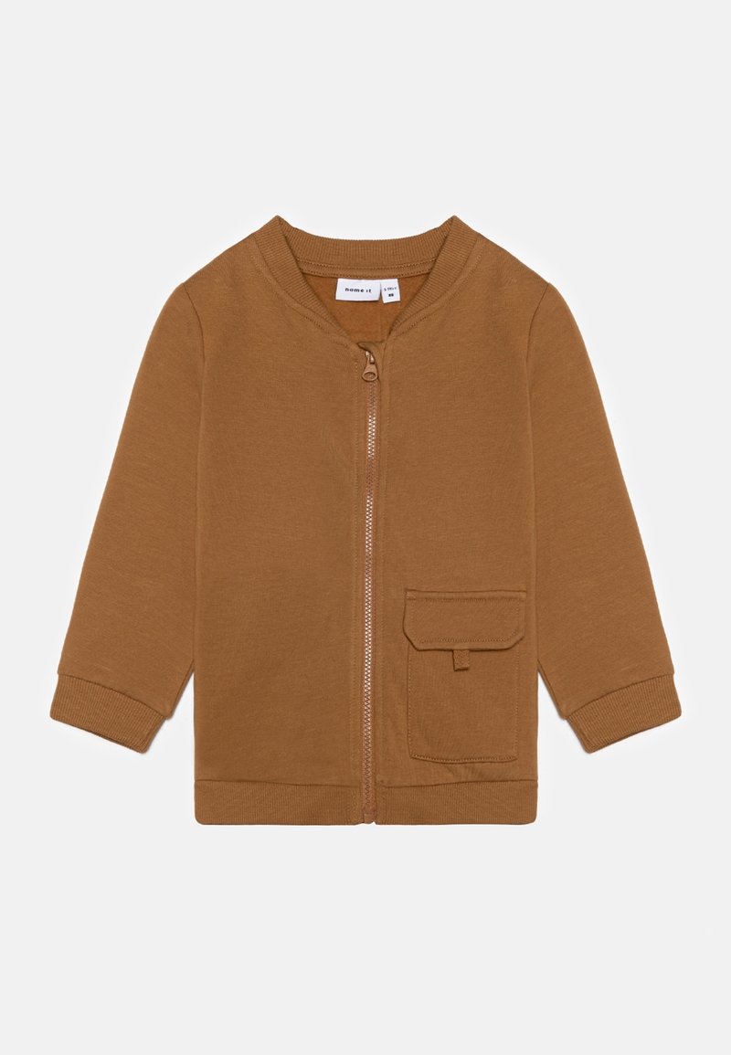 Chaqueta marrón con cremallera, hecha de un tejido suave, que presenta mangas largas, un cuello redondo, un bolsillo frontal y puños acanalados.