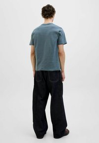 Lyseblå kortærmet t-shirt, afslappet pasform, parret med mørk brede ben jeans. Minimale syninger og afslappet design.