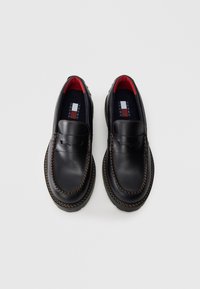 Schwarze Lederloafers mit sichtbaren Nähten, strukturiertem Obermaterial, roter Innenauskleidung und Logodetail auf den Innensohlen. Klassisches Design mit runder Zehenpartie.