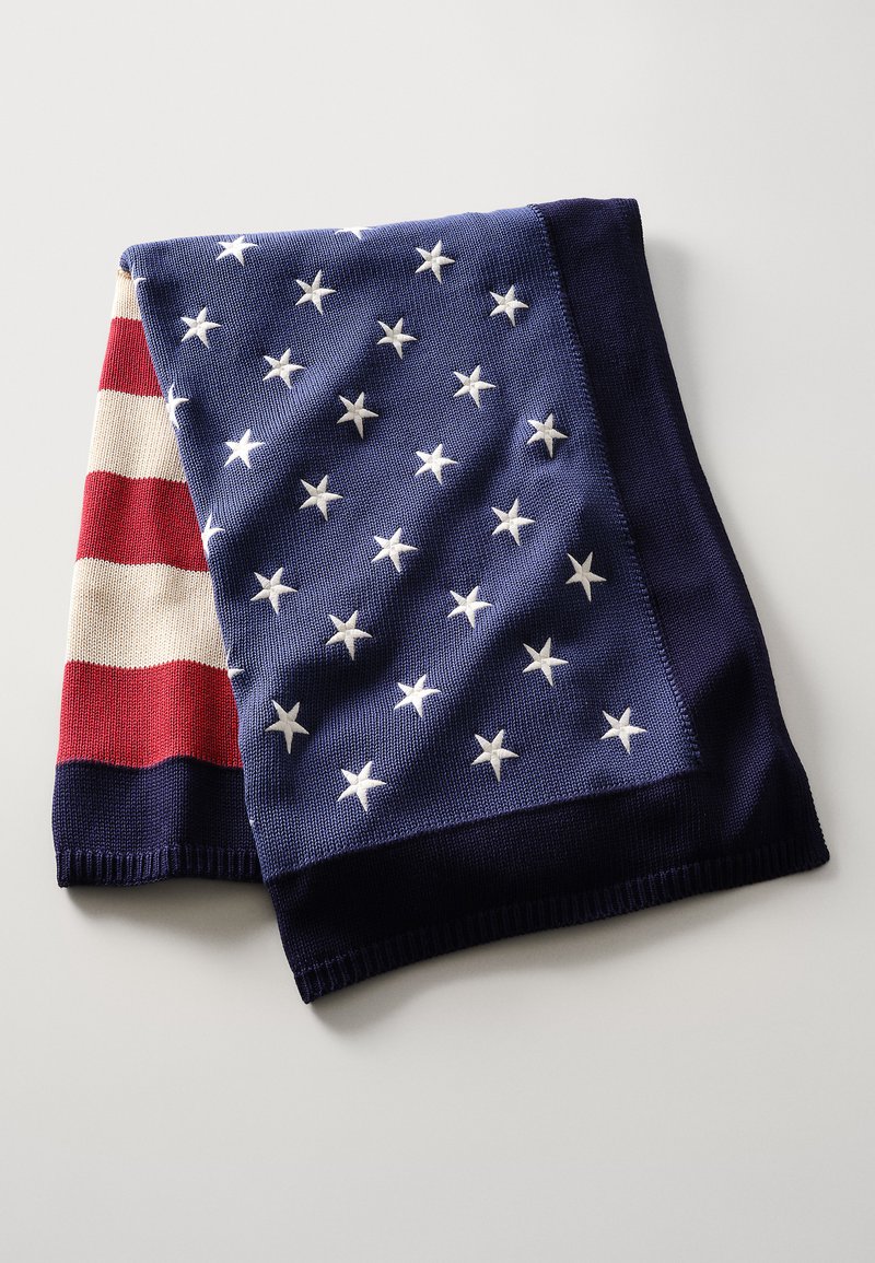 Knit blanket with alternating navy and red stripes, featuring white stars on navy. Material appears soft with visible texture and clean edges.