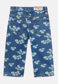 Μπλε τζιν παιδικά παντελόνια με λευκό και κίτρινο τυπώμα μαργαρίτας και δύο πίσω τσέπες, με ετικέτα «TINY» στη μέση.