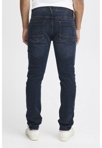 Mörka denimjeans med en figursydd design, som har två bakfickor med diskreta sömmar och en logodetail på midjan. En ren, klassisk look.