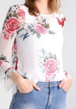 White blouse with floral pattern featuring pink roses, green leaves, and blue flowers. Transparent long sleeves and round neckline.