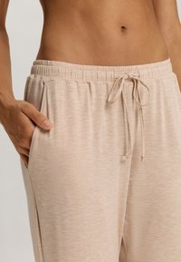 Lichtbeige, zachte stof sweatpants met een elastische tailleband, trekkoord en zijzakken. Heeft een ontspannen pasvorm en een subtiele textuur.