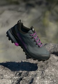Sapatilha de caminhada cinza com detalhes pretos, cordas roxas e a palavra "SCARPA" em destaque. Apresenta uma sola robusta para aderência.