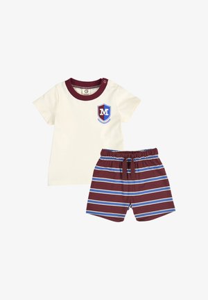 Crèmekleurig shirt met korte mouwen, bordeauxrode kraag en embleem, gecombineerd met bordeauxrode korte broek met blauw-witte horizontale strepen.