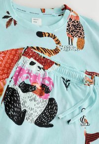 Bavlnená sada pyžama zahŕňajúca svetlomodrý top so zvieratkami a farebnými vzormi a šortky s grafikou pandy a elastickým pásom.