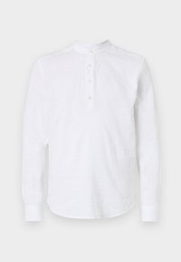 Camisa de manga larga blanca hecha de lino ligero. Presenta un cuello mao, una tapeta de botones y un dobladillo redondeado con un sutil detalle de costura.