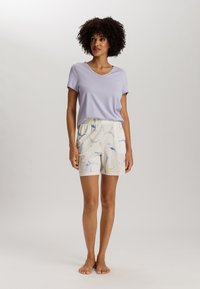 Lichtpaarse V-hals T-shirt gecombineerd met crèmekleurige shorts met kleurrijke, abstracte patronen. De stoffen zijn zacht en casual, geschikt voor loungewear.