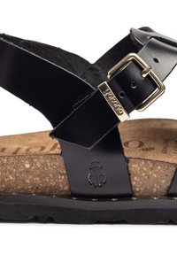 Sandalia de cuero negro con hebilla dorada, plantilla de corcho y logotipo de mariquita grabado en la correa cerca de la suela.