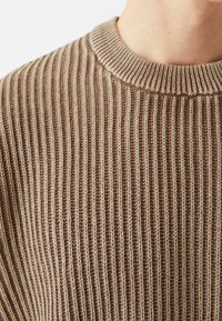 Hnědý žebrovaný pletený svetr s kulatým výstřihem, zdobený střídavými světlými a tmavými pruhy pro texturu a vizuální zajímavost.