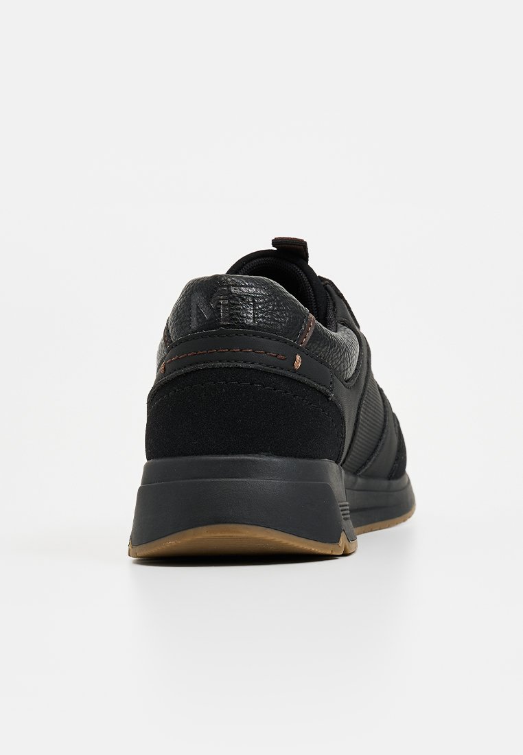 Basket noire avec partie supérieure en cuir texturé et en daim, dotée d'un col rembourré, d'une semelle en caoutchouc et d'accents de couture marron.