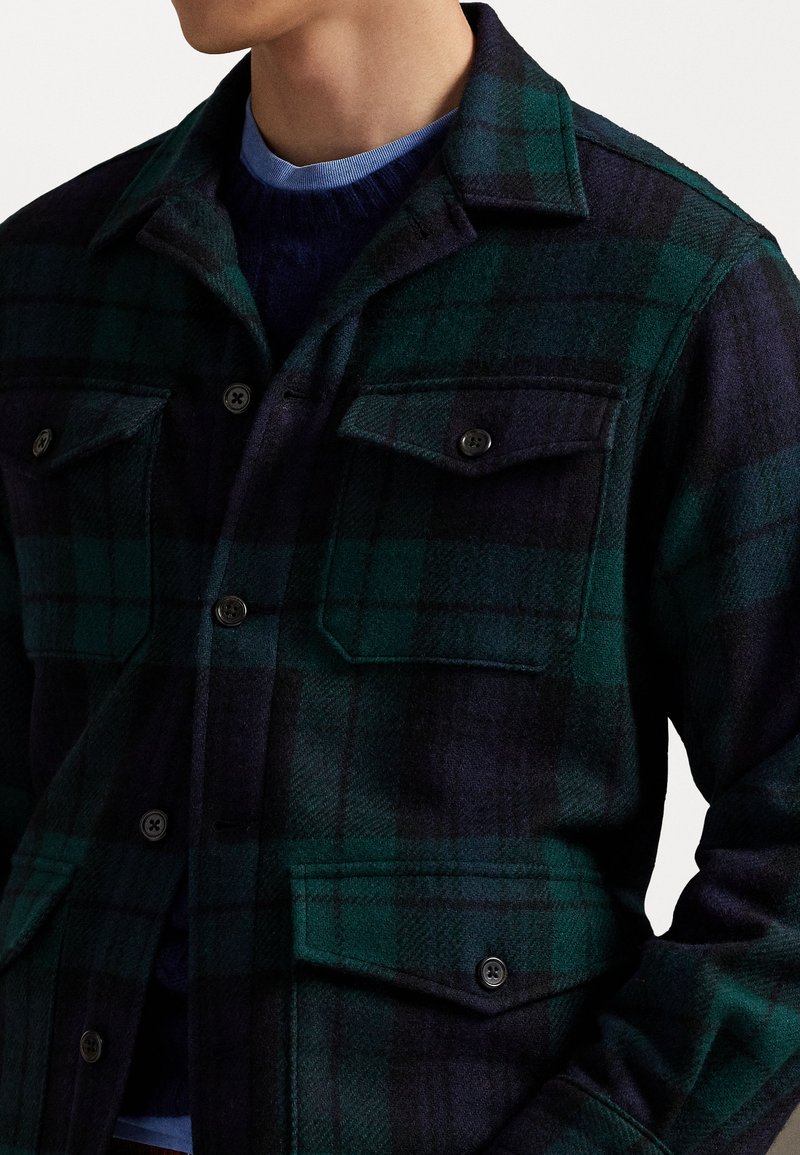 Flannel skjorte i mørkegrøn og marineblåternet med to brystlommer, en klippet krave og sorte knapper. Blød tekstur og regular fit.