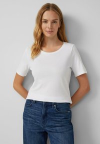 Witte t-shirt met korte mouwen en ronde hals, gemaakt van gladde katoen, gecombineerd met mid-blauwe spijkerbroek. Eenvoudig, klassiek ontwerp.