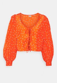 Blouse courte à manches longues orange vif avec petit imprimé floral blanc et trois fermetures à nouer à l'avant sur un fond uni.