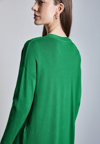 Maglione a maniche lunghe verde in maglia con vestibilità rilassata, caratterizzato da un colletto rotondo e spalle scese, che mette in evidenza una texture liscia e un design semplice.