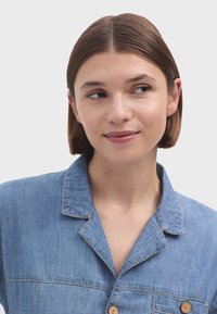 Denimová košeľa s golierom, krátkymi rukávmi a drevenými gombíkmi. Má svetlomodrú farbu s vyšívanými detailmi.
