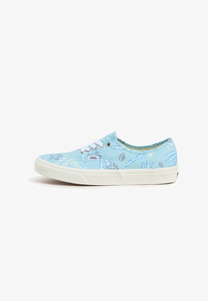 Deportivas de lona azul claro con un patrón floral en tonos más oscuros de azul, cordones blancos y suela de goma blanca. Costuras detalladas visibles.