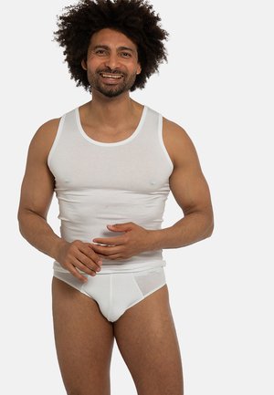 Weißes Tanktop mit breiten Trägern, kombiniert mit weißen Slips. Der Stoff wirkt glatt; schlichtes, klassisches Design ohne sichtbare Muster oder Akzente.