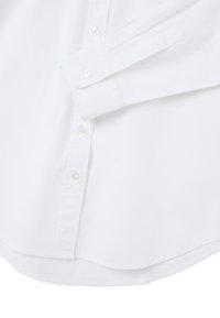 White button-up shirt featuring a standard collar, long sleeves, and a curved hem. Made of smooth fabric with clear buttons.