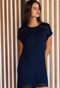Robe bleu marine avec manches courtes, détails en dentelle sur les épaules et ourlet en dentelle festonnée. Tissu doux avec une silhouette décontractée.